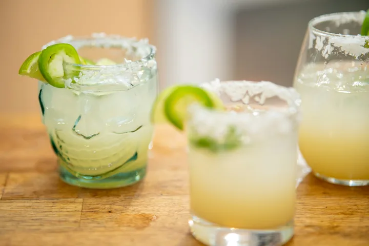 Lime-garnished margaritas on a wooden table; concept drink photography