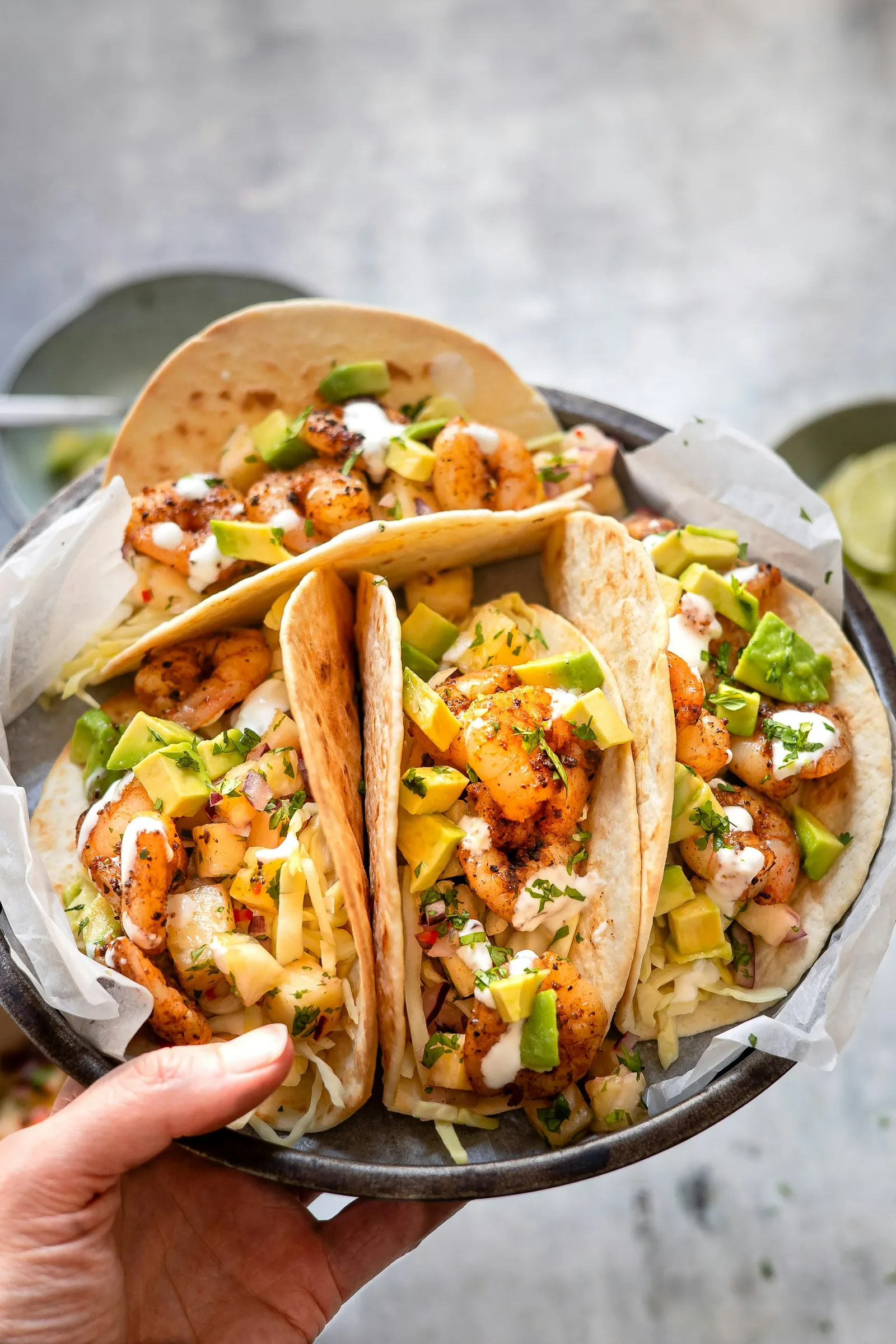 A plate of prawn tacos with avocado, cabbage and lime; concept food photography