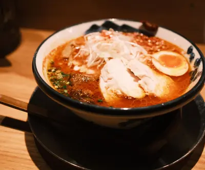 Reference photograph of ramen in red broth with egg, sliced meat and shredded spring onion