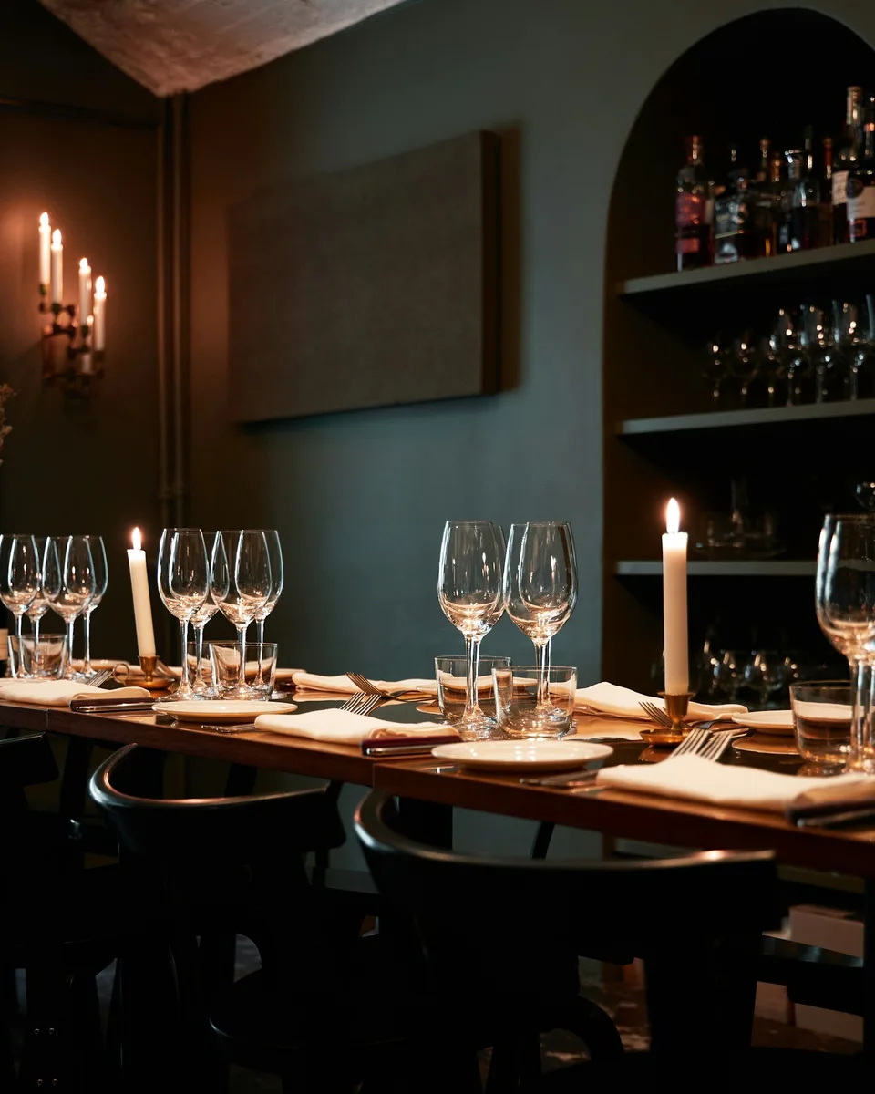A dining room with candlelit tables, wine glasses and shelves of wine bottles